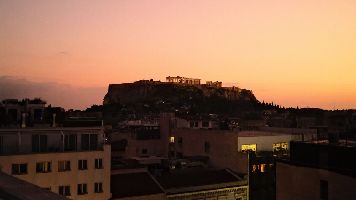 A stunning view of Athens featuring the Acropolis against a vibrant sunset sky.