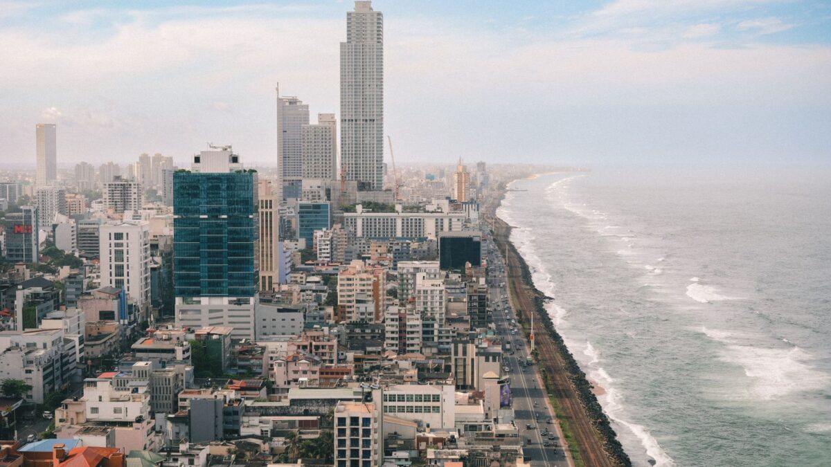 Aerial view of Colombo's vibrant skyline against the Indian Ocean's dramatic waves.
