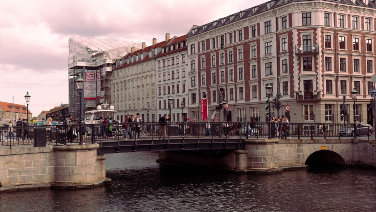 Scenic view of a historic bridge crossing a canal in a European old town, bustling with people.