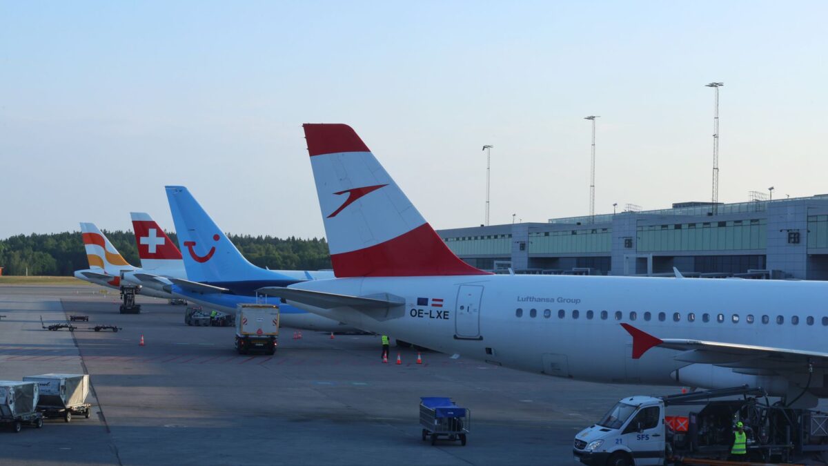 Multiple airplanes lined up at Oslo Airport terminal in daylight.