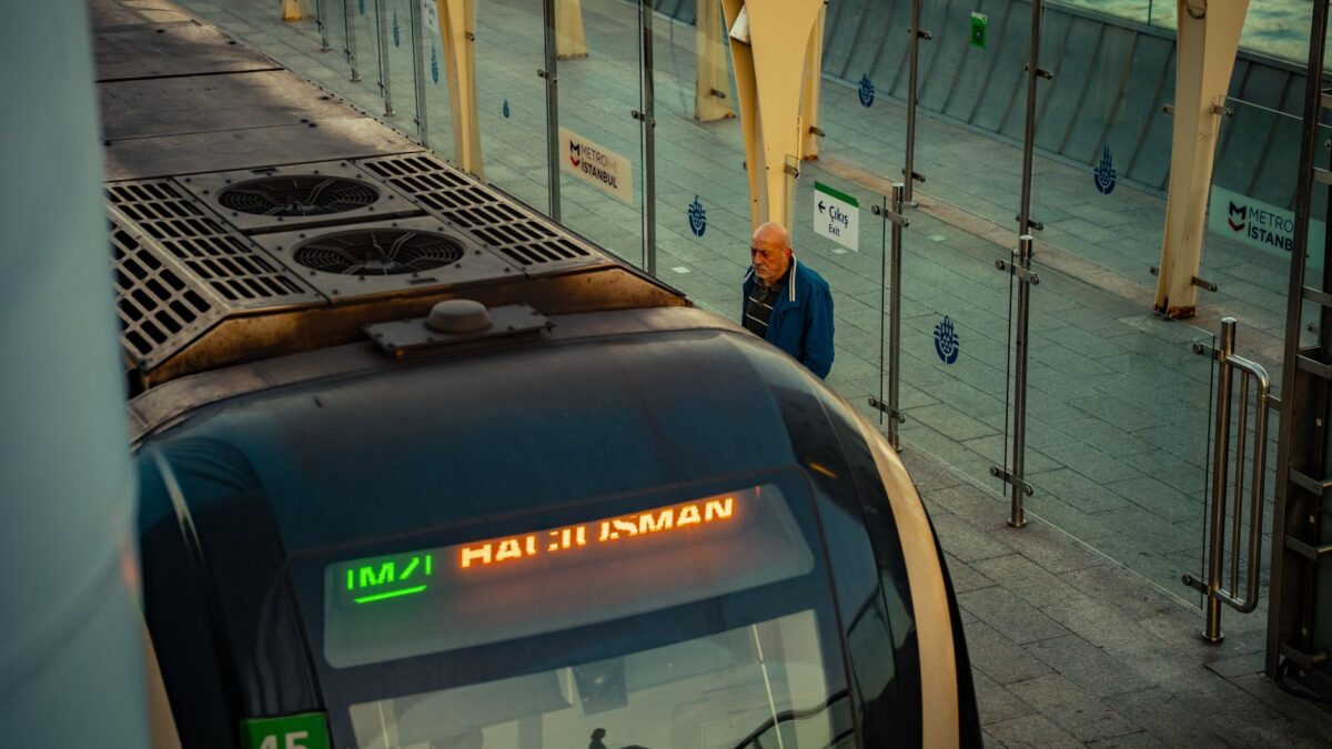 A metro train at Istanbul station with a man waiting on the platform, showcasing urban transport.
