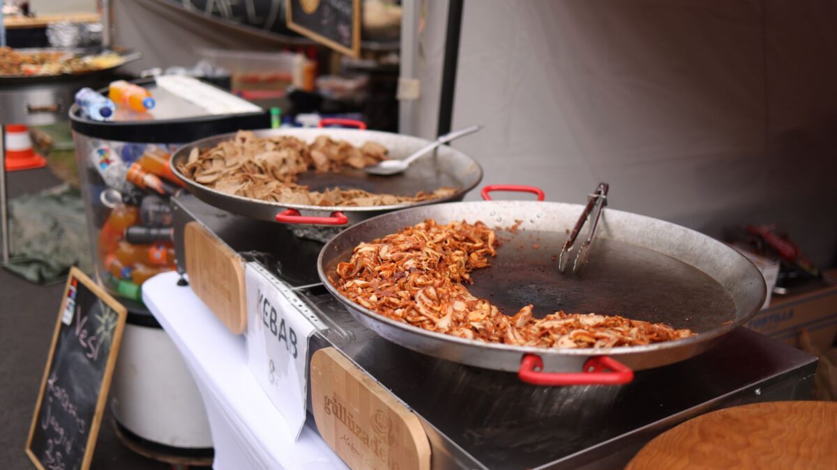 Close-up shot of a street food stall with kebab preparation in large pans, offering a vibrant dining experience.