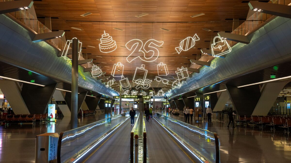 Interior of Hamad International Airport in Doha with celebratory decorations featuring neon icons and numbers.