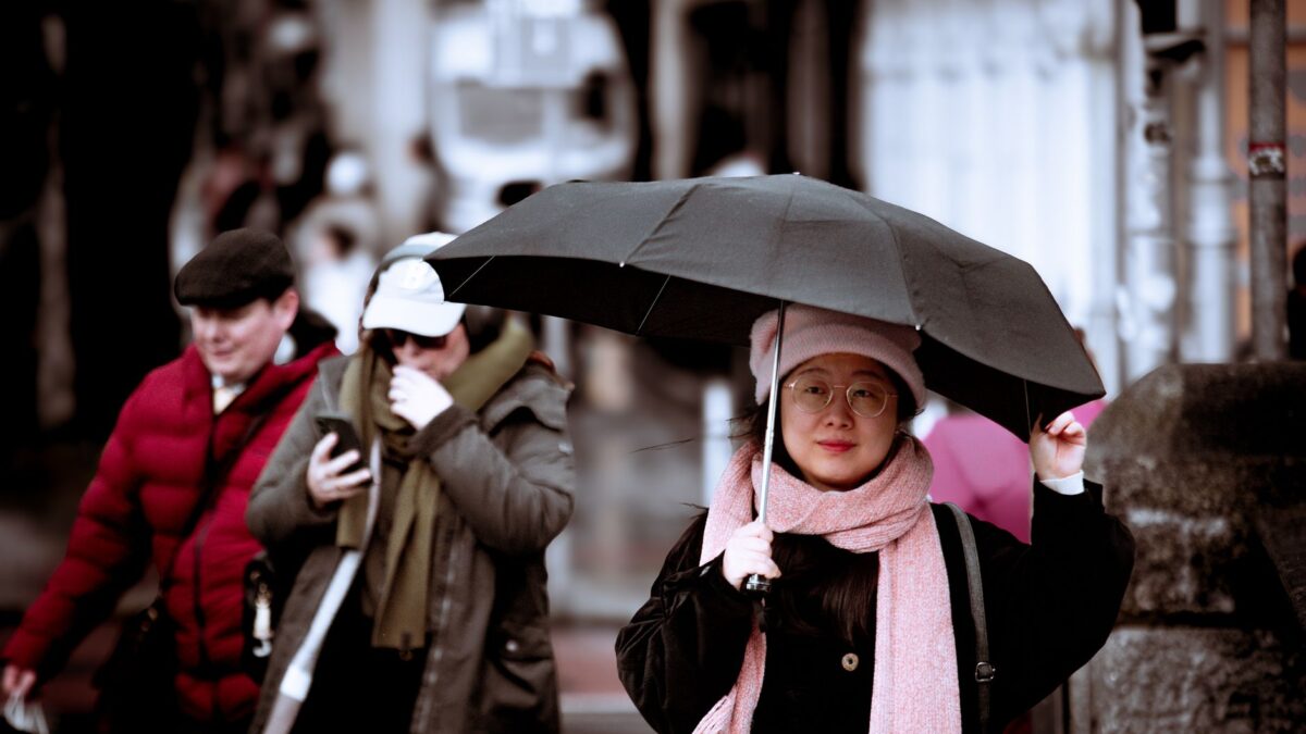 A candid street scene in Dublin, Ireland, featuring pedestrians in winter attire and umbrellas.