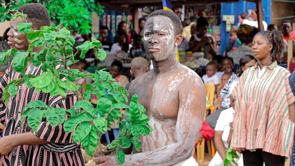 Colorful parade with traditional attire and body paint in Amedzofe, Ghana, showcasing cultural heritage.