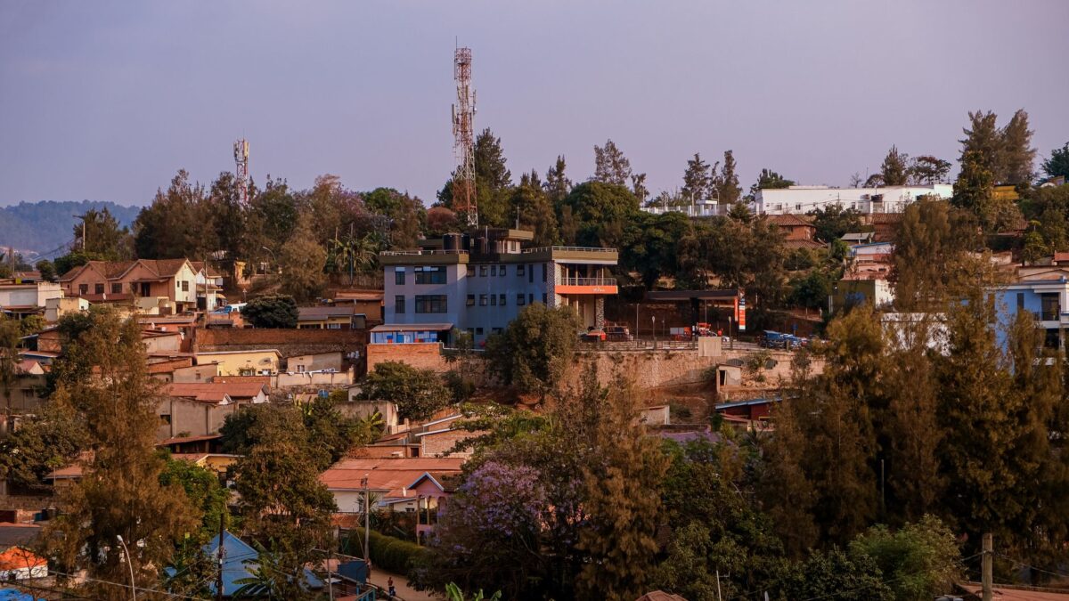 A vibrant urban scene showcasing buildings, vegetation, and distant hills under a clear sky.