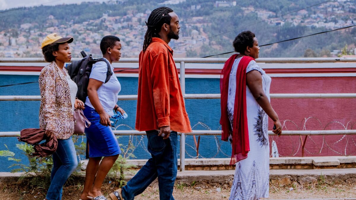Group of four adults walking on city sidewalk with vibrant background, showcasing cultural diversity.