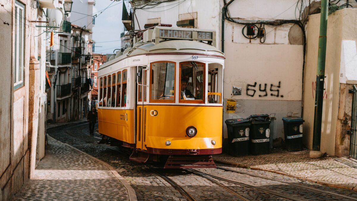 Historic yellow tram on Lisbon's cobblestone street, capturing a classic European scene.