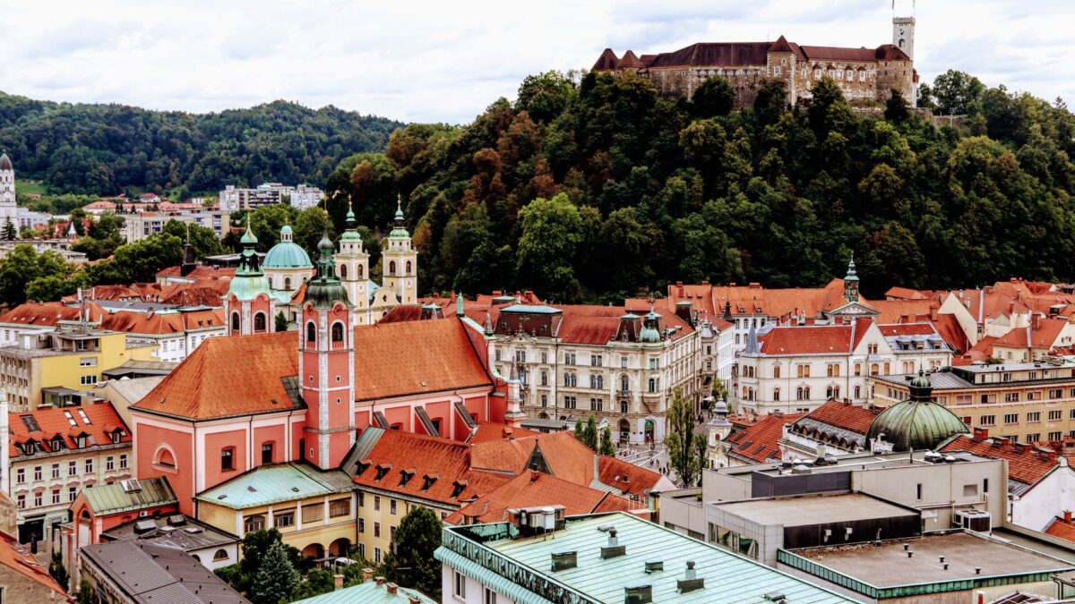 A scenic view of Ljubljana's vibrant old town with the famous castle atop a green hill.