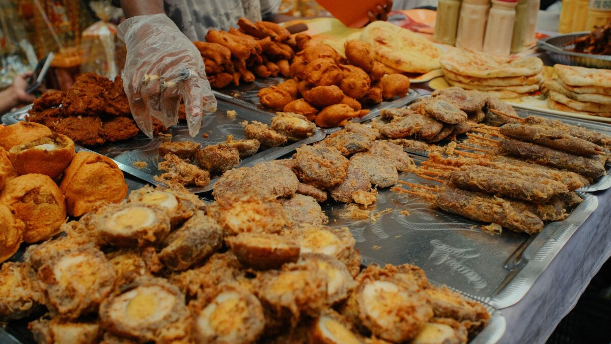 A variety of traditional foods displayed at a bustling Dhaka Iftar market during Ramadan.