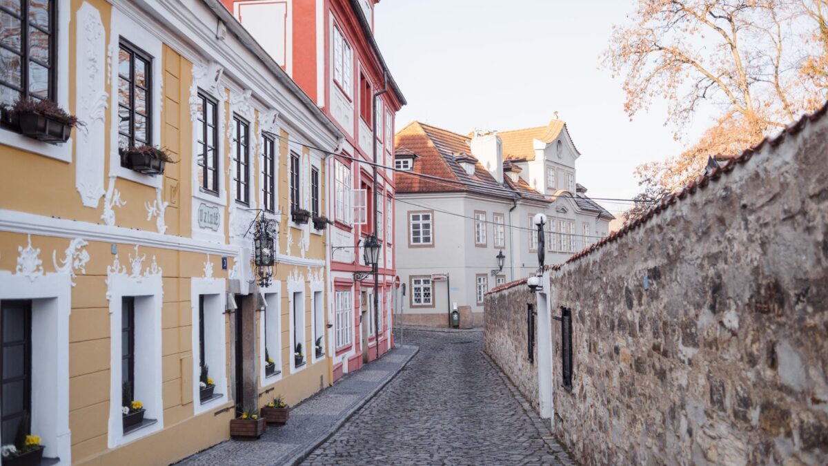 Cobblestone walkway between stone wall and aged house exteriors with ornament in fall in Prague Czech Republic