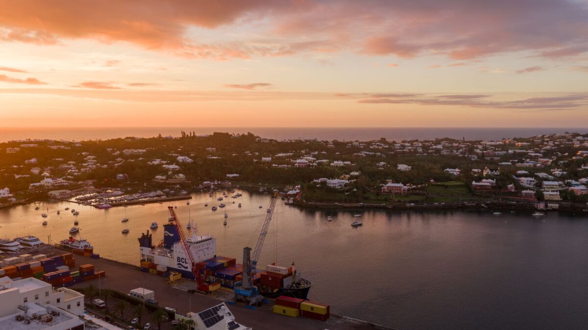 A stunning aerial view of Bermuda harbor at sunset, showcasing boats and colorful houses.