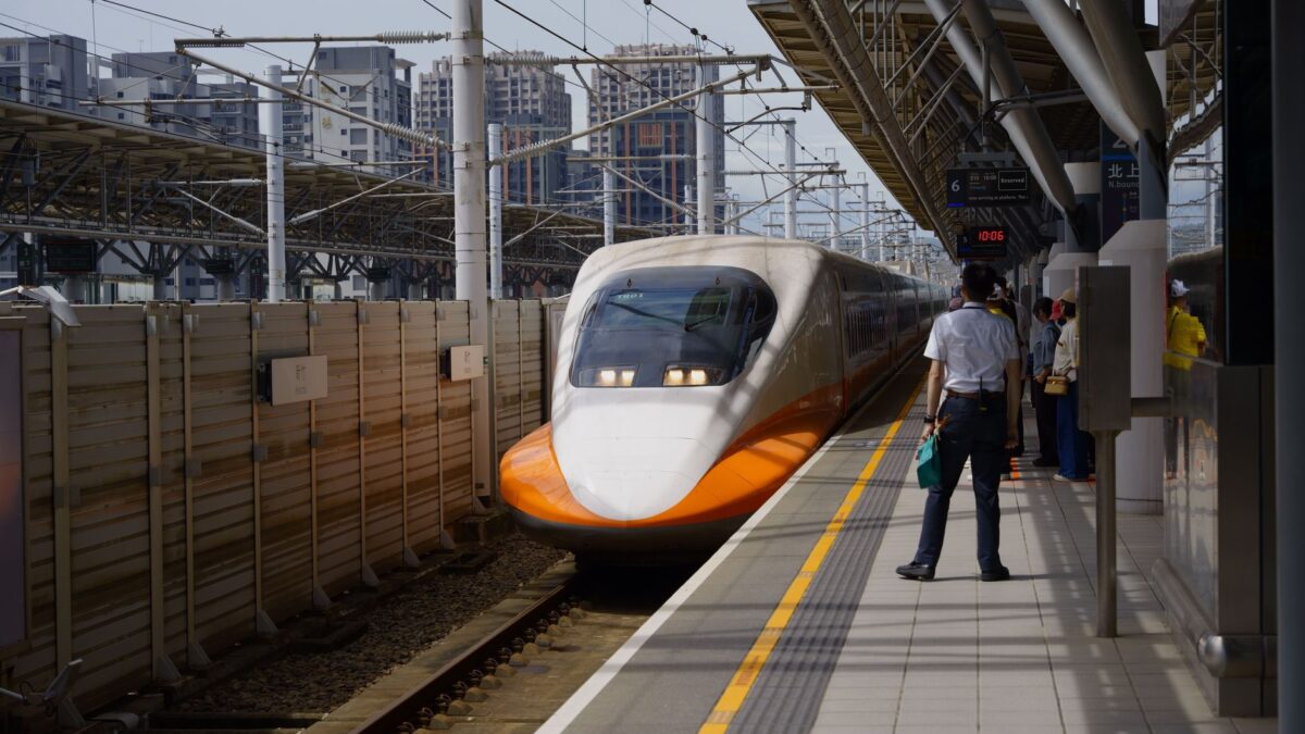 A high-speed train approaches Hsinchu Station in Taiwan on a sunny day.