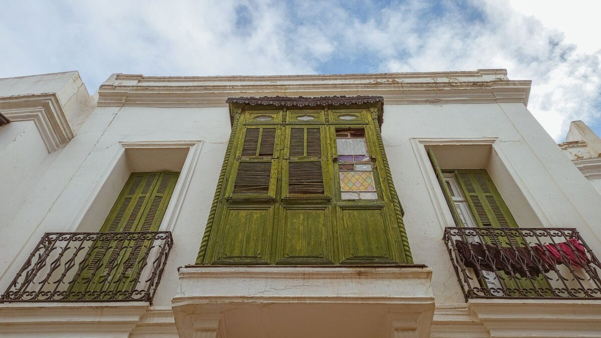 A charming view of a building facade in Tunis with green shutters and Mediterranean style.