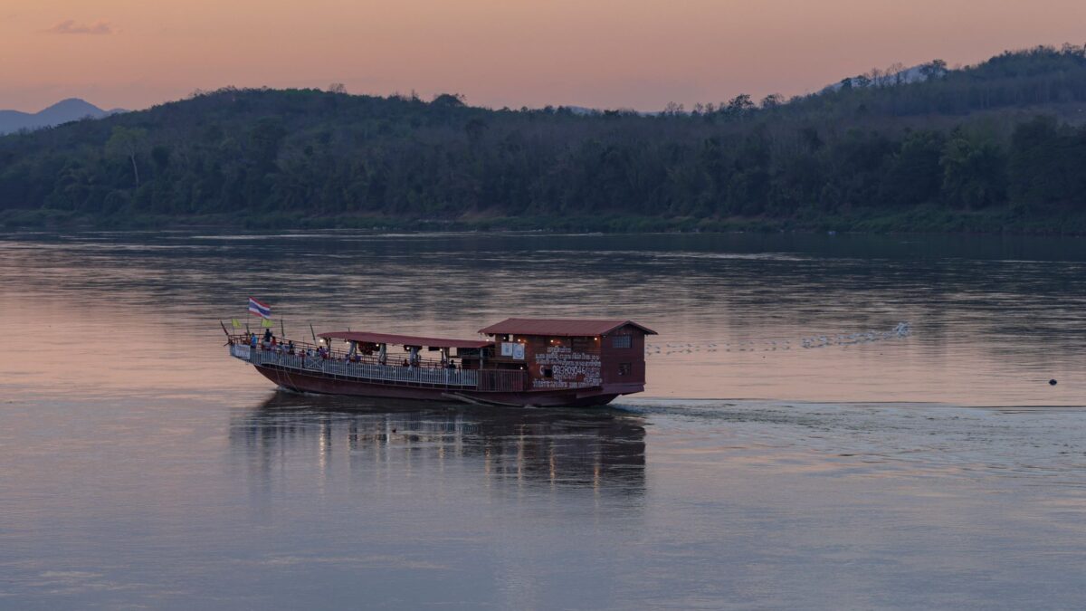 A tranquil evening view of a boat on the Mekong River at sunset in Chiang Khan, Thailand.
