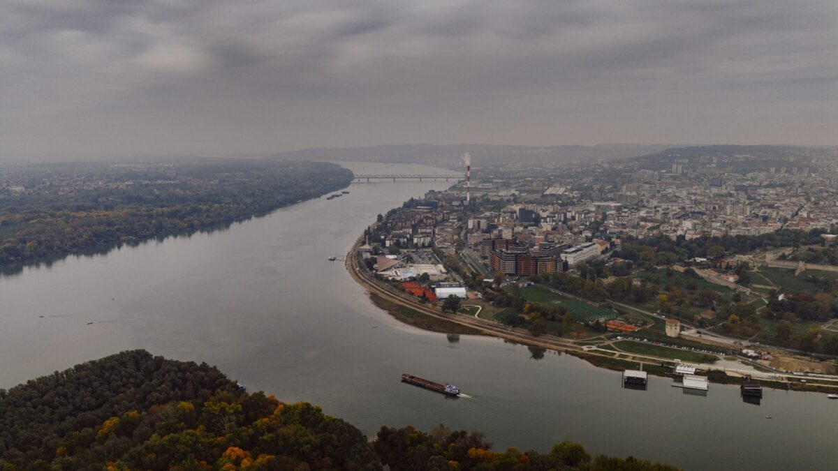 Aerial view of the cityscape and river in Belgrade, Serbia, under cloudy skies.