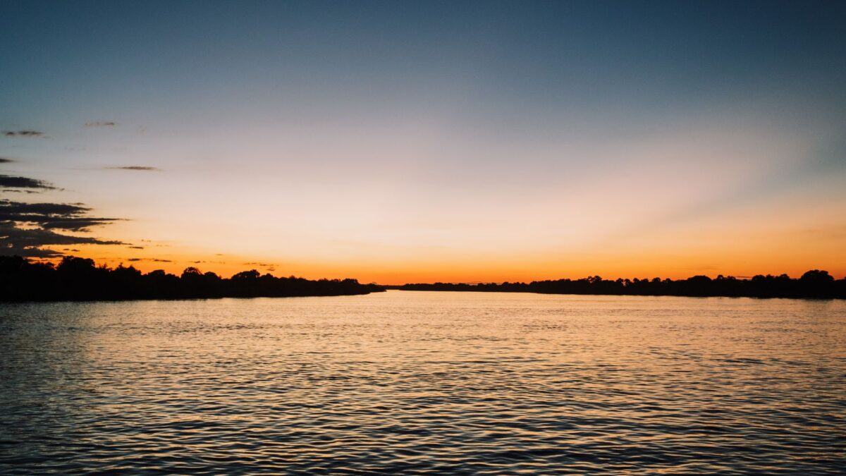 Serene sunset over a tranquil lake with vibrant sky and gentle water ripples.