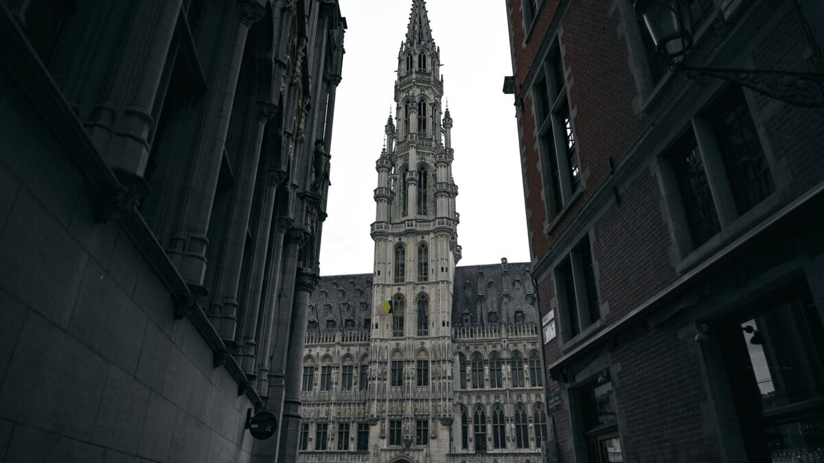Dramatic view of the Brussels Town Hall in Gothic style, framed by narrow streets.
