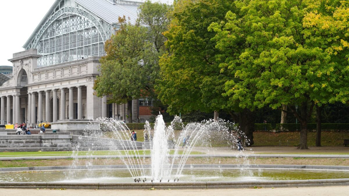 A scenic view of a fountain with the historic Brussels arcade in the background.