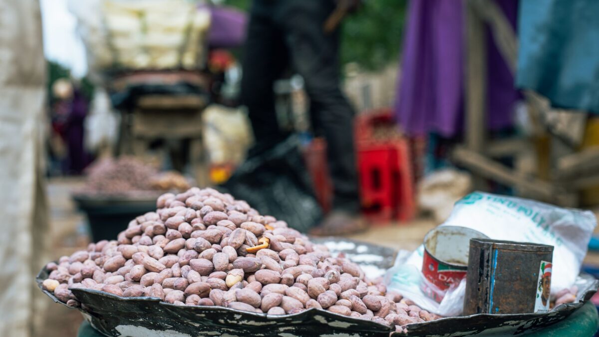 Close-up of roasted peanuts in a bustling outdoor market, showcasing lively street commerce.