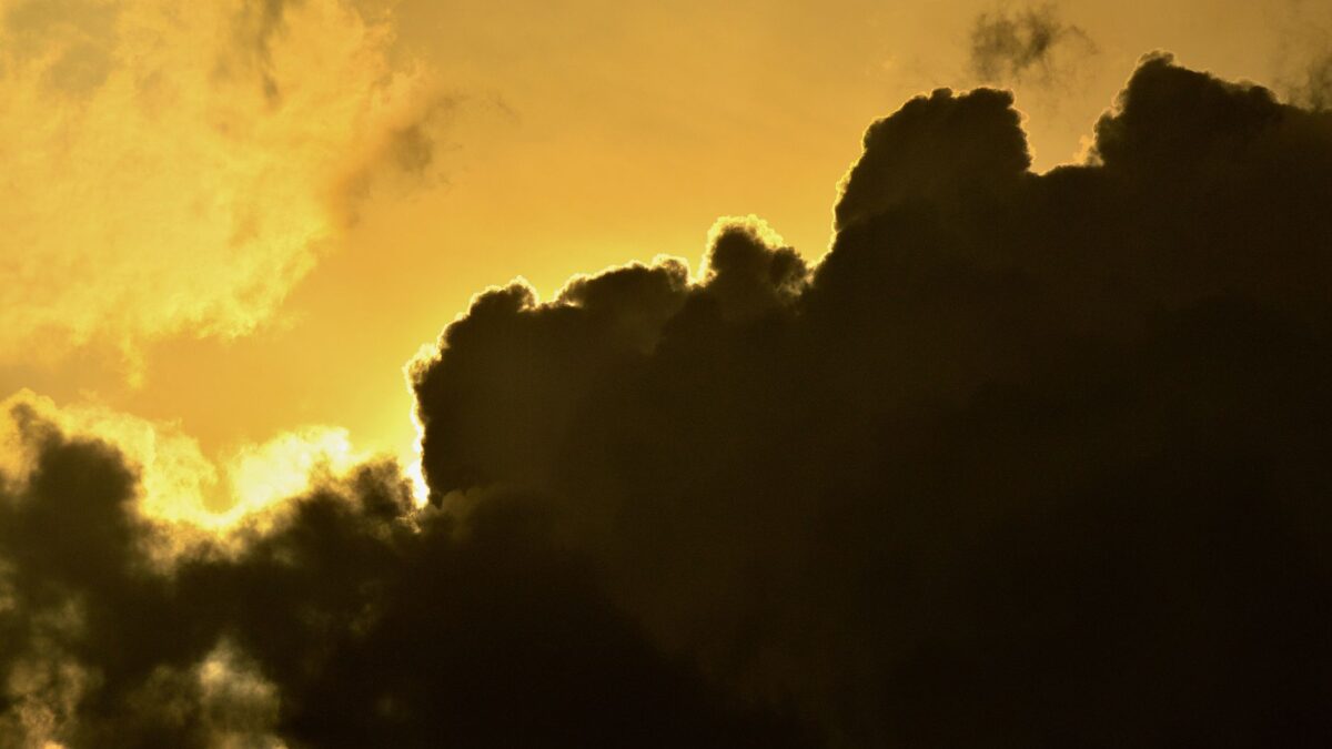 A dramatic scene of dark clouds outlined by the golden light of sunset, creating an awe-inspiring sky.