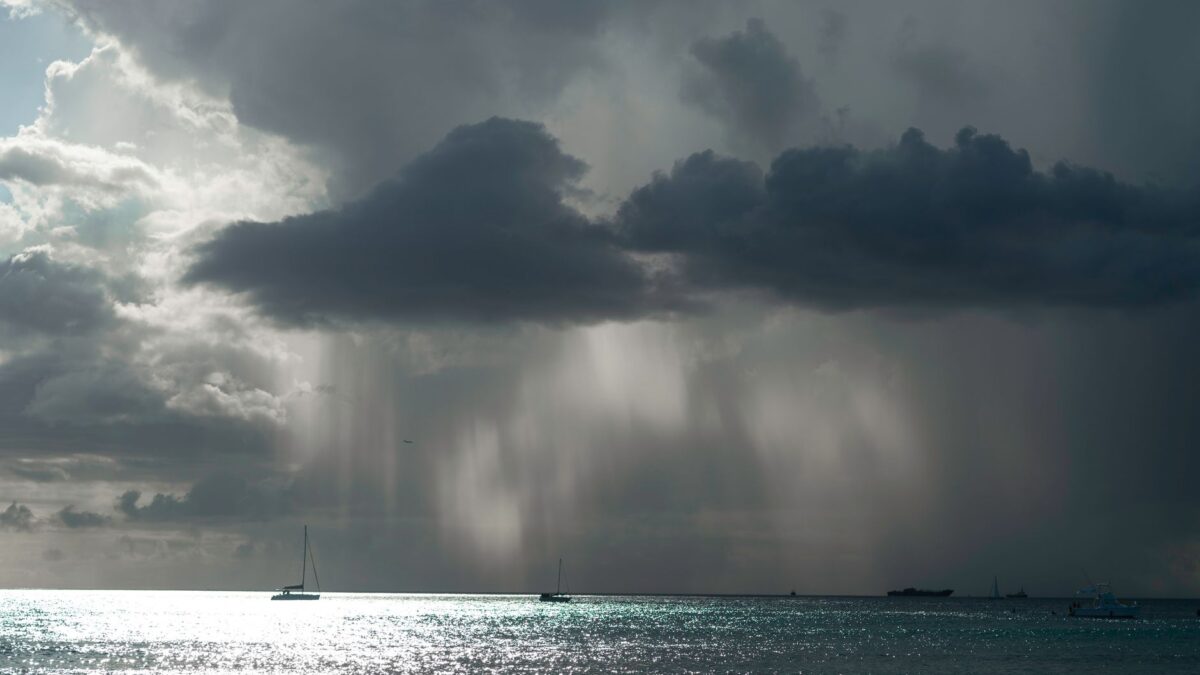 A powerful seascape featuring storm clouds, boats, and a shimmering sea, showcasing nature's drama.