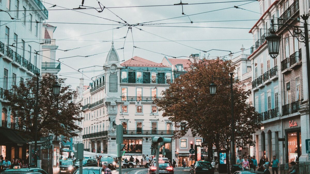 Explore a bustling street scene in Lisbon, Portugal, featuring stunning classic architecture and lively urban traffic.
