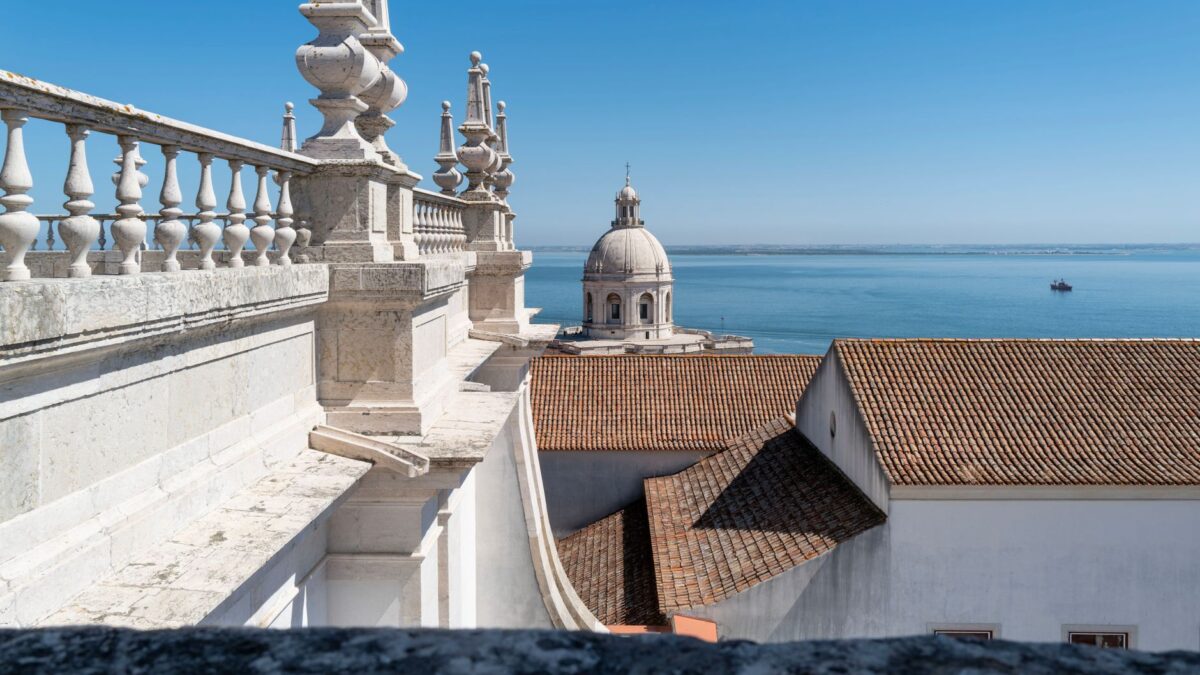A breathtaking view of Lisbon's National Pantheon with the Tagus River in the background under a clear blue sky.