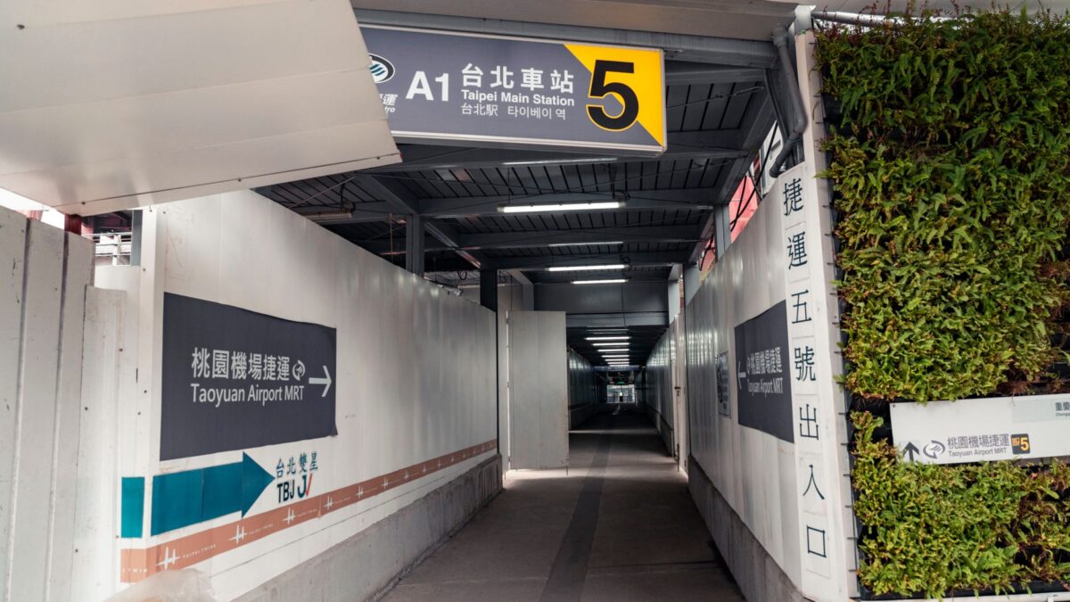 Covered walkway leading to Taipei Main Station Exit 5 with signs to Taoyuan Airport MRT.