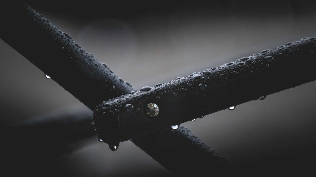 Closeup of part of wet steel fence covered with clear pure transparent raindrops