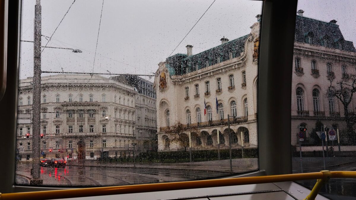 View of Vienna's historic buildings through rainy tram windows, capturing the city's urban charm.
