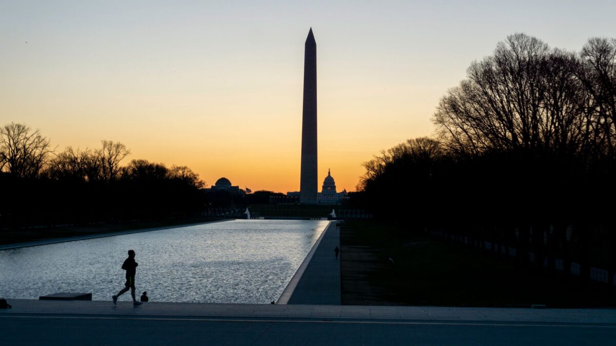 A jogger's silhouette with Washington Monument backdrop at dusk in Washington DC's National Mall.